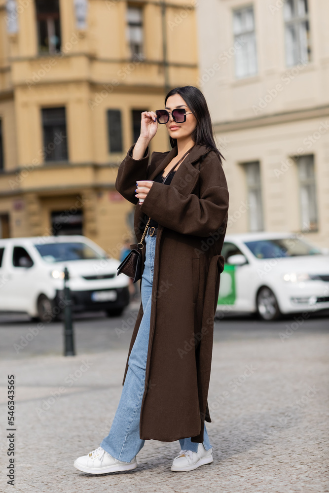 Stylish young tourist holding paper cup and sunglasses on street in Prague. Stylish young tourist holding paper cup and sunglasses on street in Prague.