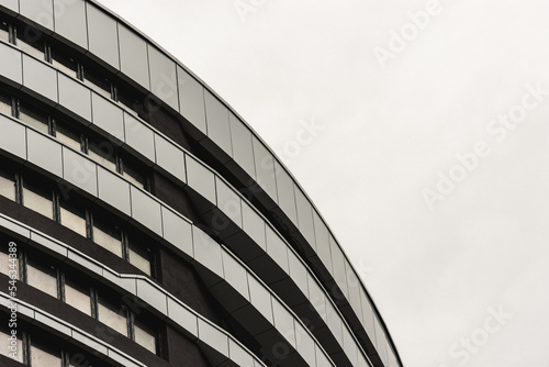 Modern curved corporate building architecture design with windows on a cloudy day
