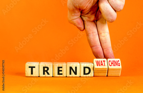 Trend or trendwatching symbol. Concept words Trend and trendwatching on wooden cubes. Businessman hand. Beautiful orange table orange background. Business trend or trendwatching concept. Copy space. photo