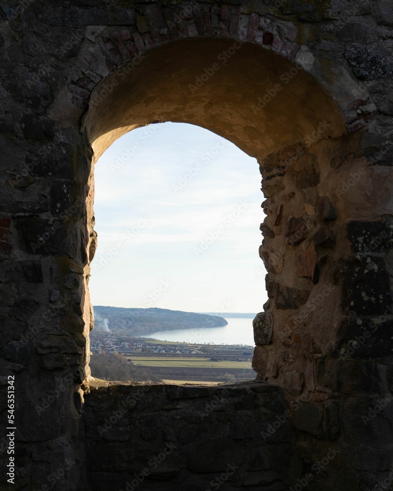Window view of a hilly field and the sea from Brahehus Castle ruin in Sweden