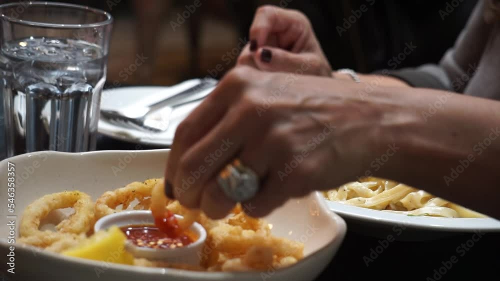 a person eating pasta Italian restaurant eating calamari fried appetizer Italian cuisine lunch time woman's hands mature brown woman eating pasta and fish with dipping sauce delicious food date night a person eating pasta Italian restaurant eating calamari fried appetizer Italian cuisine lunch time woman's hands mature brown woman eating pasta and fish with dipping sauce delicious food date night