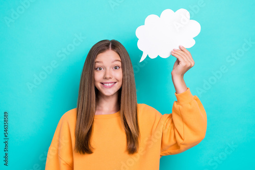 Photo of intelligent cute funny smiling girl wear orange sweatshirt hold white paper bubble empty space opinion isolated on cyan color background