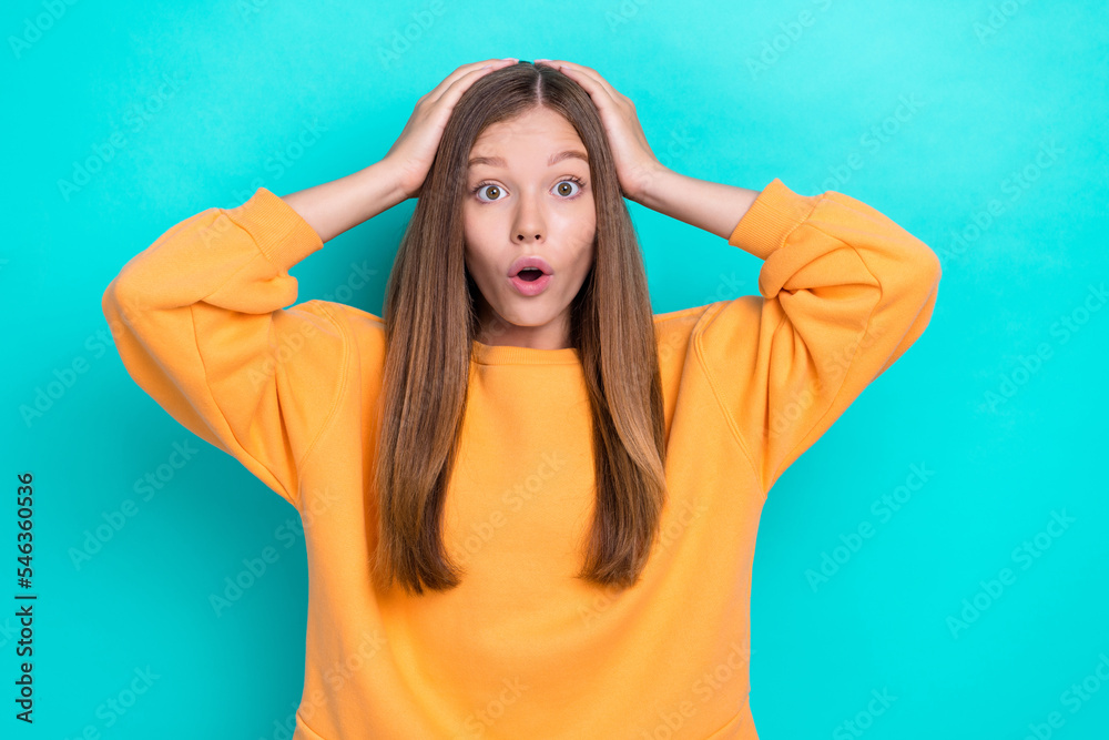 Photo of young funny teenager brown hair beautiful girl wear orange sweater touch head surprised news inflation isolated on cyan color background Photo of young funny teenager brown hair beautiful girl wear orange sweater touch head surprised news inflation isolated on cyan color background