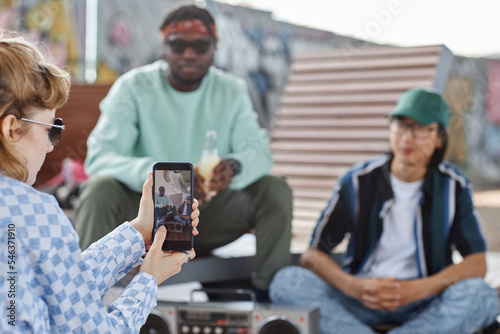 Close up of young woman filming video with friends for social media via smartphone