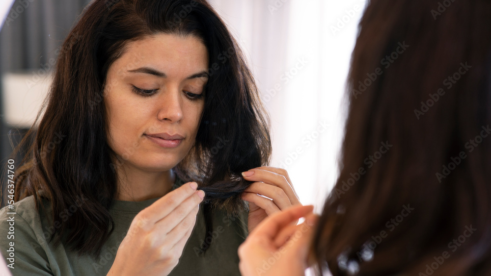 Girl touching her hair while looking in the mirror. Hair care Girl touching her hair while looking in the mirror. Hair care