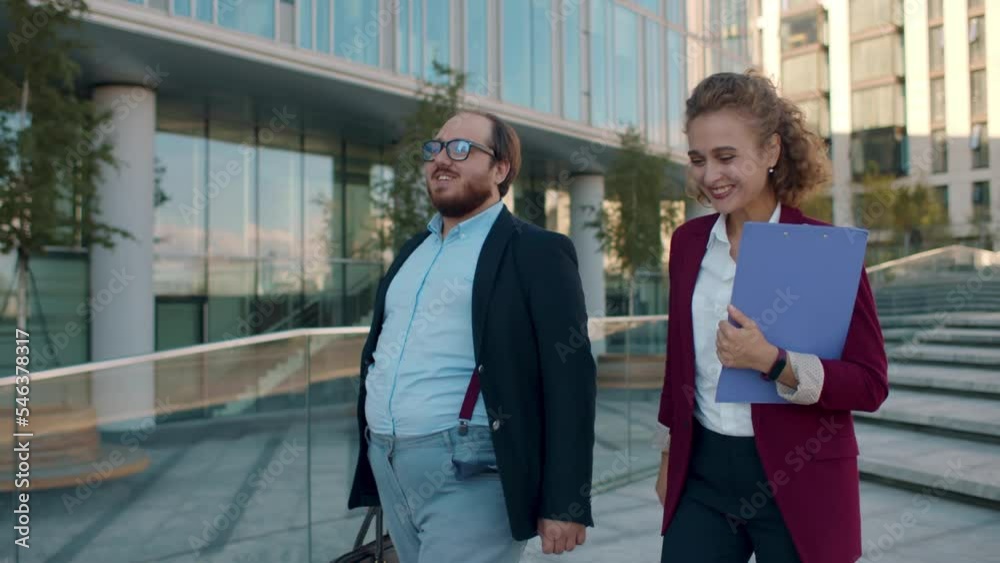 Confident coworkers discussing work walking outside business center. Realtime