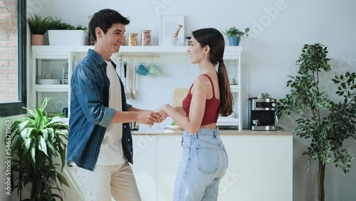 Video of lovely young couple cooking together dancing in the kitchen at home.