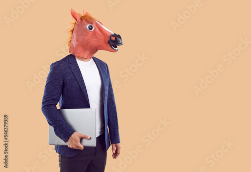 Canvas Print Freak bizarre anonymous guy with horse head holding laptop isolated on beige background