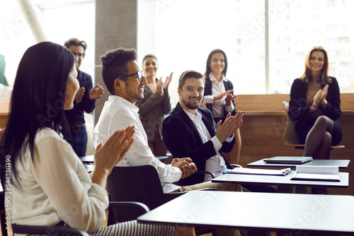 Business people applaud cheers man on business meeting or training in bright modern office. Colleagues congratulate man clapping hands on business achievements, excellent work results or promotion.