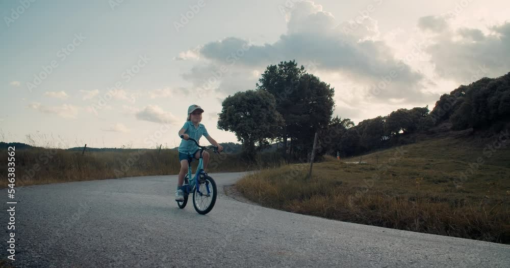 Child boy ride a bicycle on empty mountain road in rural environment on summer Child boy ride a bicycle on empty mountain road in rural environment on summer
