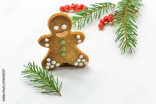 gingerbread man cookies decorated with royal icing, with icing sugar and fir branh on white background. Christmas food, pastry background. New Year theme. Merry Christmas and Happy New Year Holidays