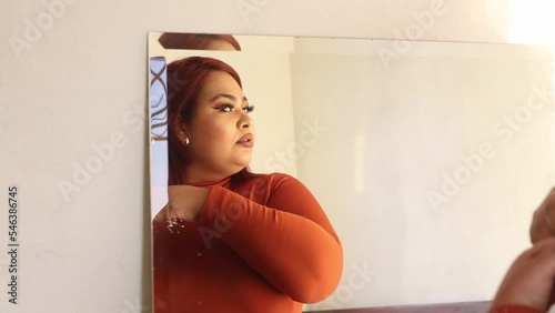 Hispanic plus size woman combing her hair in front of a mirror. mexican chubby