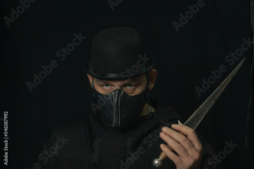 Scary man with knife or dagger creepy mask and hat in the dark