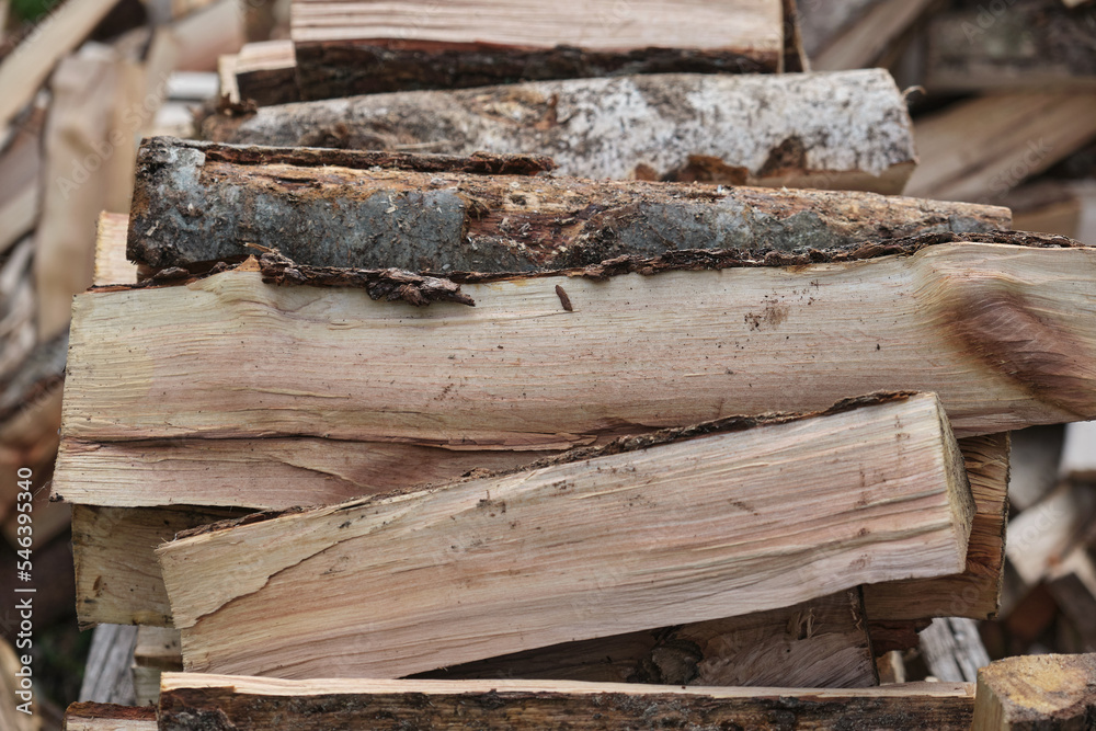 A man worker loads firewood into a wheelbarrow for heating the house which are unloaded in the yard A man worker loads firewood into a wheelbarrow for heating the house which are unloaded in the yard