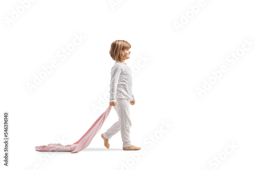Full length profile shot of a little girl in pajamas walking and holding a ping blanket