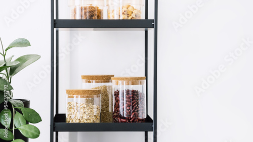 cereals, pasta and beans in glass jars with lid on shelf in kitchen photo