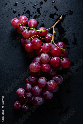Branch of red grapes on a dark background.