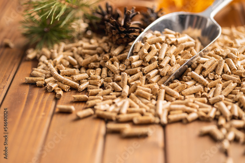 Wooden pellets in scoop on wooden table.