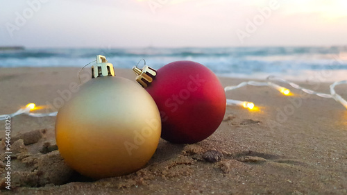 Christmas decorations in the form of a golden and red ball on the sand on the beach.