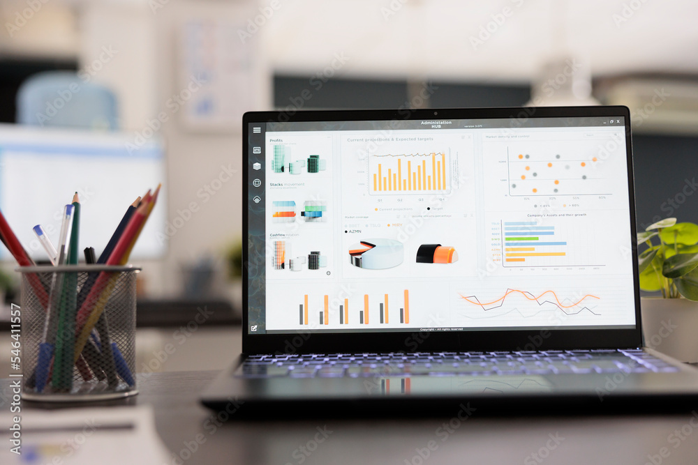 Portable computer with statistical infographics on a desk in an empty ...
