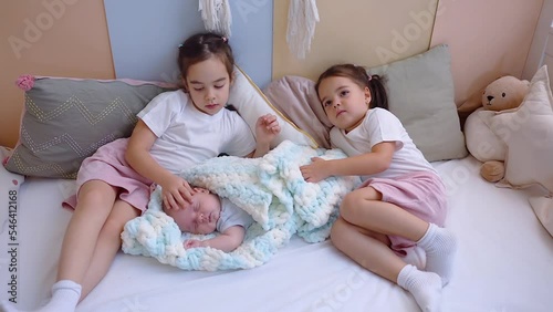 Three little siblings kids lying in bed at home, newborn baby with sisters.