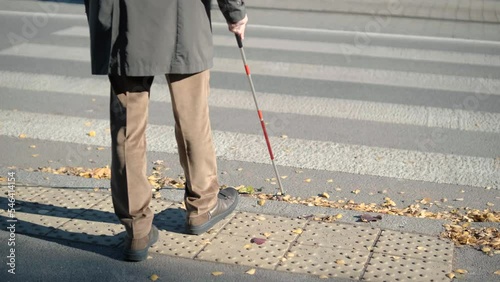 Lone blind man detecting tactile tiles, walking to pedestrian crossing safe road