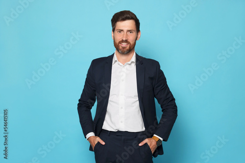 Portrait of handsome bearded man in suit on light blue background