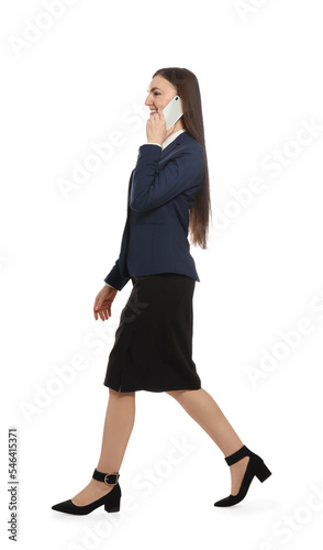 Young businesswoman talking on smartphone while walking against white background