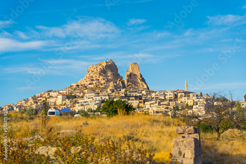 Scenic landscape of Cappadocia, Turkey with buildings and unusual rocky structures. Bright clear sky. Grassy plain in the foreground. Tourist destination. Horizontal shot. High quality photo