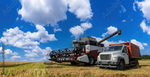 Agricultural harvester. Harvesting wheat. Combine for harvesting grain under blue sky. Agricultural combine and truck in field. Agricultural machinery for farmers. Combine for harvesting grain crops