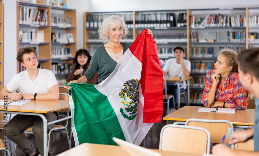 Interesting story about Mexico while teaching high school students in school library. Teacher holds the flag of Mexico in her hands
