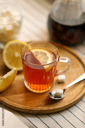 Glass mug of aromatic tea with lemon on table, closeup