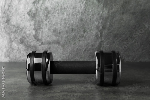 Metal dumbbell on table against grey background. Space for text