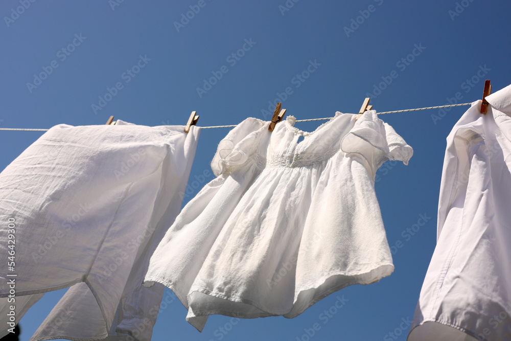 Clean clothes hanging on washing line against sky, low angle view. Drying laundry - obrazy, fototapety, plakaty 
