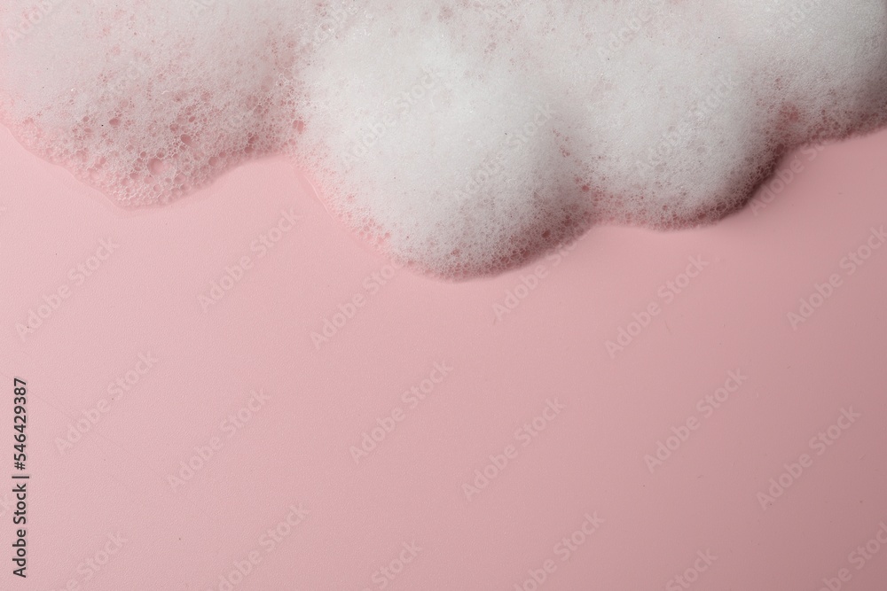 Fototapeta premium Fluffy soap foam on pink background, above view. Space for text