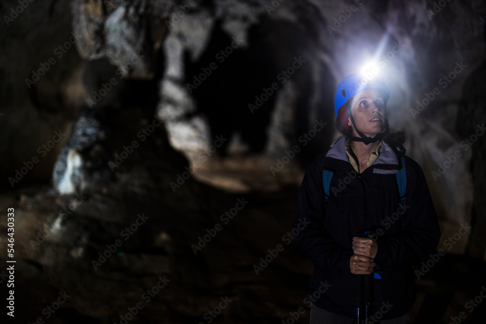 Female Speleologist Admiring Scenic Cave Interior full of Stalactites and Stalagmites
