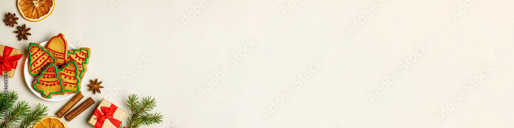Christmas border. Gingerbread cookies, spices, christmas tree branches and decorations on white wooden background. Top view, flat lay, Xmas greeting banner with copy space Christmas border. Gingerbread cookies, spices, christmas tree branches and decorations on white wooden background. Top view, flat lay, Xmas greeting banner with copy space
