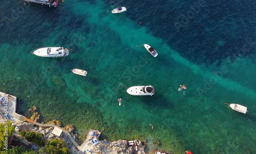 Aerial view of the coast of Mediterranean Sea. Beach resort vacation. Drone view of kayaks, sups, boats, swimming people in blue water.