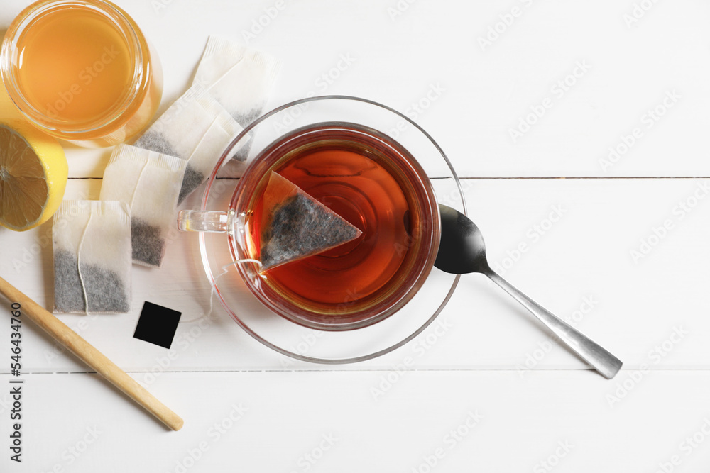 Tea bags, honey and lemon near cup of hot drink on white wooden table, flat lay Tea bags, honey and lemon near cup of hot drink on white wooden table, flat lay