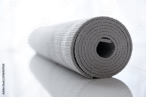 Rolled karemat or fitness mat on tiled floor, closeup