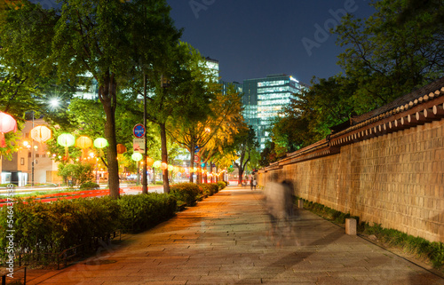 The stone wall of Gyeongbokgung Palace and the night view of the street lit by lotus lanterns.