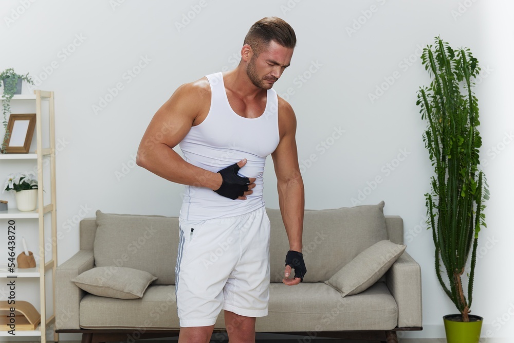 Man sports stomach and side pain, muscle growth exercises, pumped up man fitness trainer works out at home, the concept of health and body beauty Man sports stomach and side pain, muscle growth exercises, pumped up man fitness trainer works out at home, the concept of health and body beauty