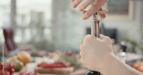 Female unscrews opens bottle of red wine opener in hands in close up photo