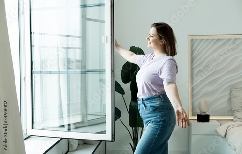 Fototapeta Naklejka Na Ścianę i Meble -  Woman Standing By Bedroom Window And Opening Curtains
