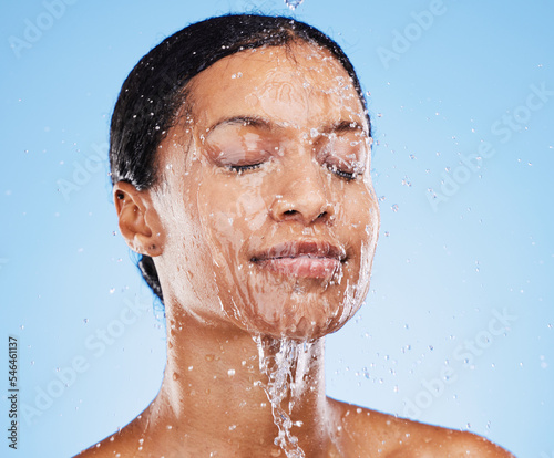 Foto Woman, shower and water splash on face for skincare hydration or clean hygiene against blue studio background