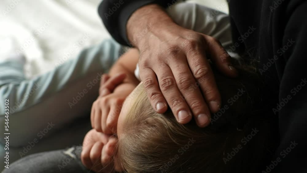 Close-up cropped shot of unrecognizable loving caring father comforting offended unhappy little daughter, showing love and care, expressing support, hugging stroking hair at home, slow motion.