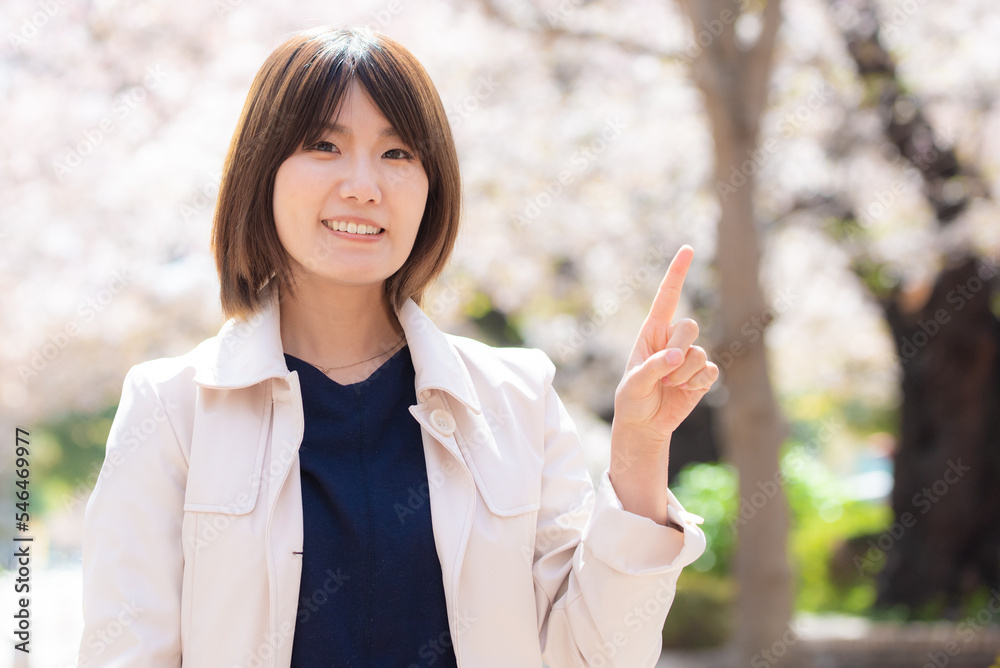 桜の咲いた春の屋外にいる笑顔の日本人女性 桜の咲いた春の屋外にいる笑顔の日本人女性
