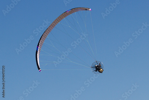 Person riding a paraglider against the blue sky in the background