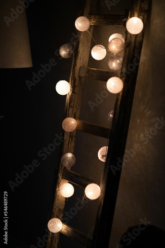 Vertical shot of decorative circle lamps tied on a wooden ladder photo