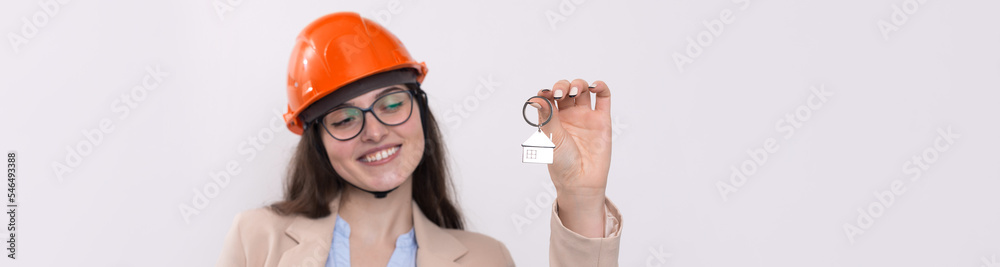 A girl in a construction helmet holds a house. Realtor on a white background. A girl in a construction helmet holds a house. Realtor on a white background.